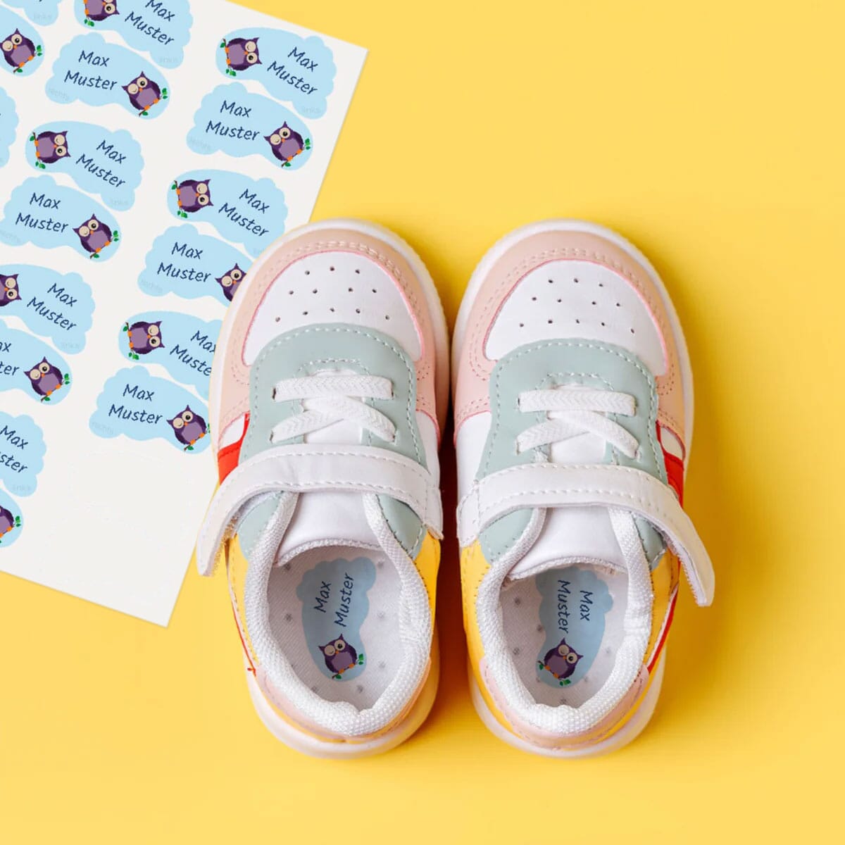 Personalisierte Schuh-Etiketten neben Kinderschuhen im Detail